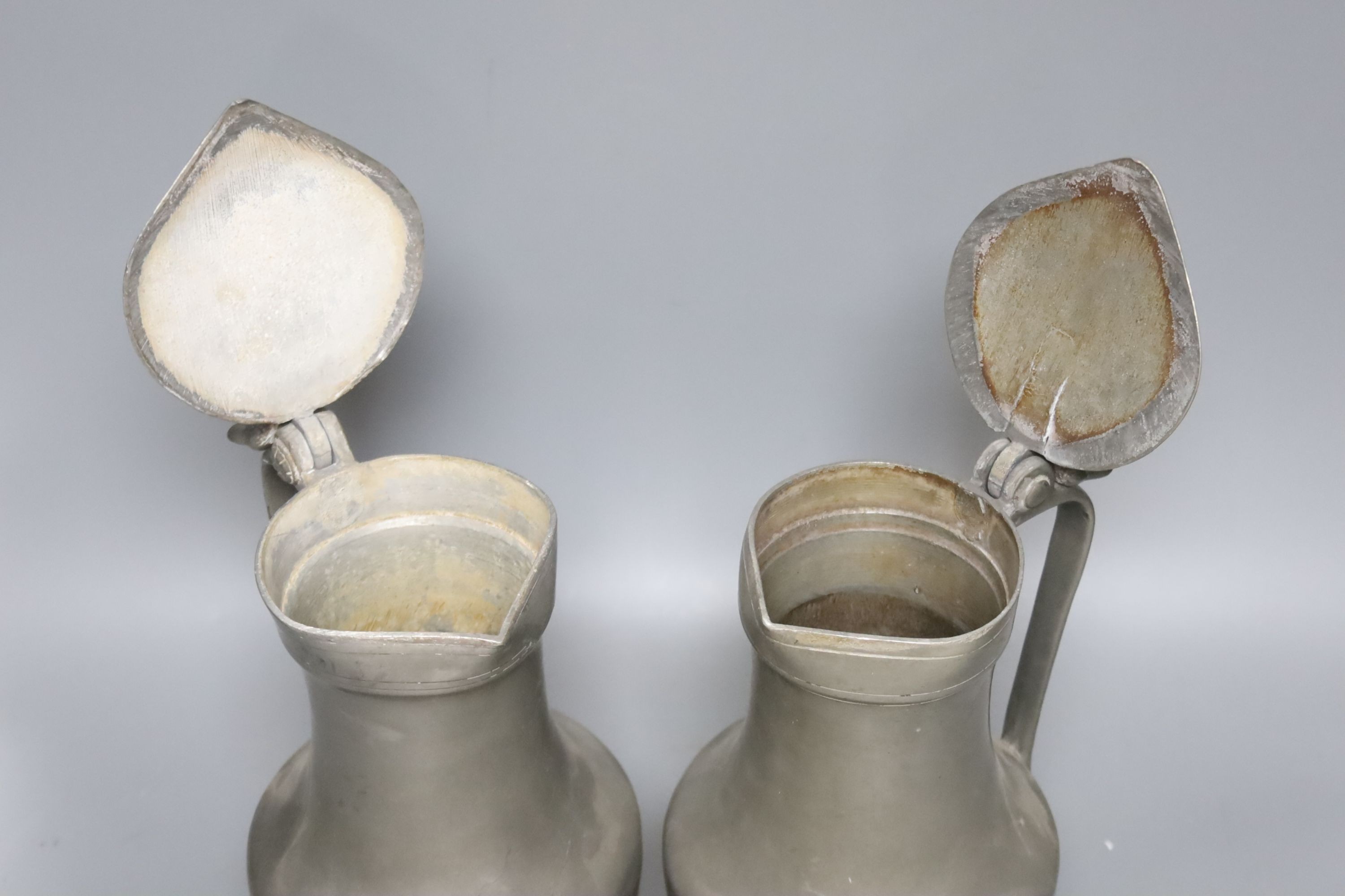 An 18th century French lidded pewter jug with double acorn thumbpiece and another similar jug, tallest 27cm